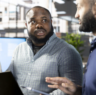 Manager looking at laptop screen with workers, showing them researching key data needed for finding business insights and finishing project task. Management executives analyzing data on notebook